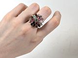 la main d'une femme tenant une bague ornée d'une fleur