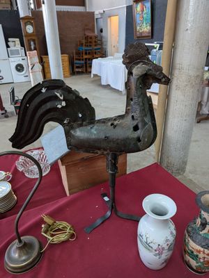 a rooster statue on a table with vases on it