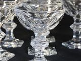 several clear glass goblets are lined up on a black surface