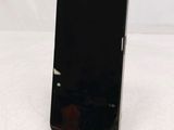 a black cell phone sitting on a stand on a white surface
