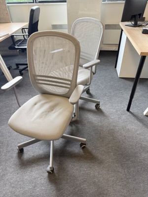 une chaise de bureau blanche placée devant un bureau d'ordinateur