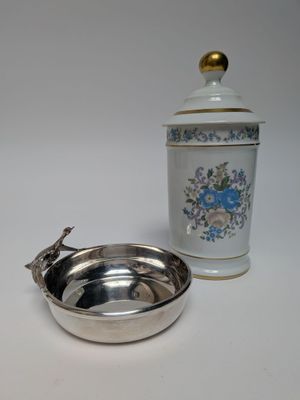un bol en argent et un récipient en argent posés sur une table blanche