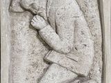un gros plan sur la statue d'un homme assis à genoux