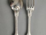 two silver spoons and a fork on a table