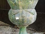 un grand vase vert posé sur une grille métallique