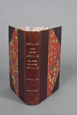 an open book with a red cover sitting on top of a table