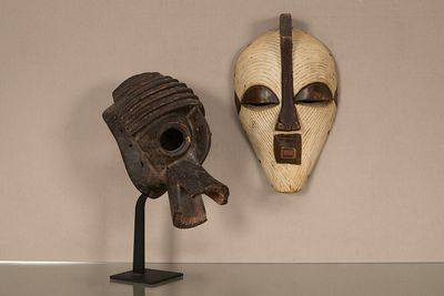 deux masques en bois exposés sur une table en verre