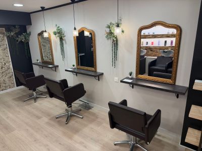a photo of a hair salon with chairs and mirrors