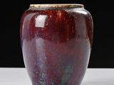 a red vase sitting on a table with a black background