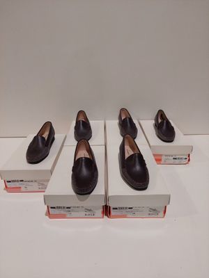 Quatre paires de chaussures noires sont exposées dans une vitrine.