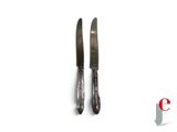 two knives that are next to each other on a white surface
