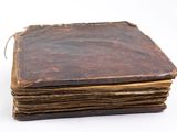 an old book is sitting on top of a white surface