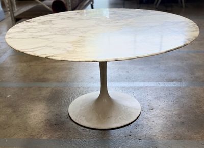 une table en marbre blanc avec un piètement noir, posée sur un sol carrelé