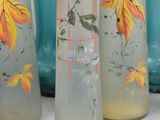 five vases that have been painted with leaves on them