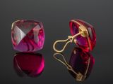 une paire de boucles d'oreilles en verre rouge et violet posées sur une surface noire
