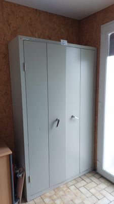 un placard situé dans un coin de la pièce, muni d'une porte coulissante en verre