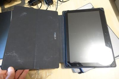 a person holding a tablet and a laptop on a table