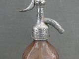 a brown glass bottle with a metal handle on a table