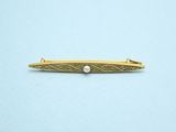 a gold tie bar with a pearl in the center