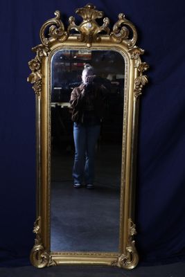 a gold framed mirror with a man taking a picture in it