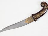 a knife with a decorative handle on a white surface