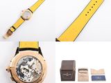 the watch is yellow and has a black strap and a watch box