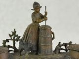 a bronze statue of a woman with a dog and a barrel
