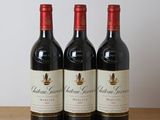 three bottles of red wine sit on a wooden table