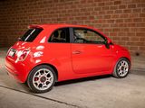 a small red car parked in front of a brick wall