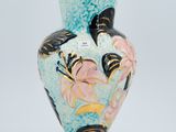 a blue vase with flowers and butterflies on it on a white surface