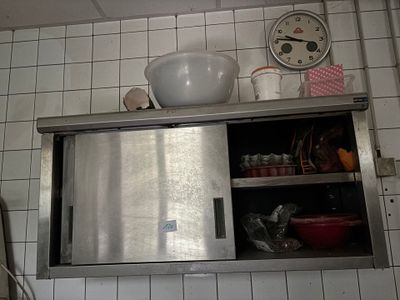 un placard en acier inoxydable dans une cuisine, avec une horloge accrochée au mur