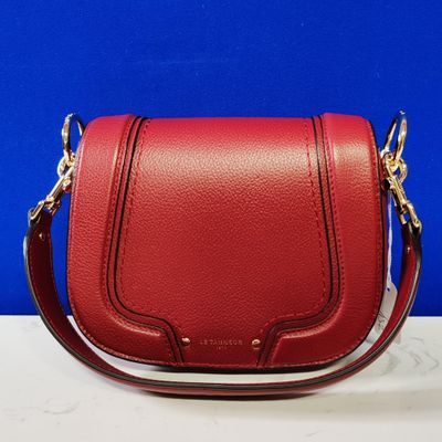 a close up of a red handbag on a white table