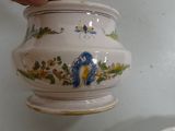 a person holding a small vase with a blue flower on it