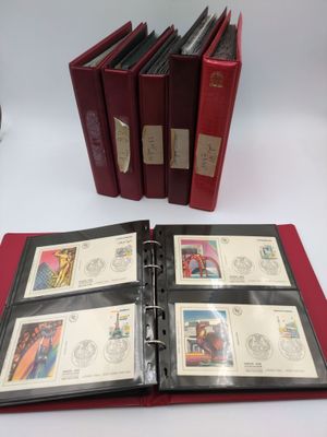 an open red binder sitting on top of a table next to a stack of stamps