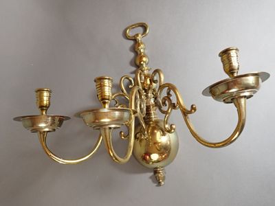 un lustre en or accroché au mur, à côté d'une bougie