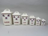 four white canisters with red flowers on them sitting on a white surface