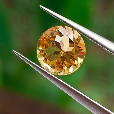 an image of a close up of a yellow diamond being held by a pair of pliers