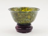 un bol vert contenant des fleurs jaunes, posé sur un socle en bois