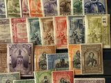 a pile of old postage stamps sitting on top of a wooden table