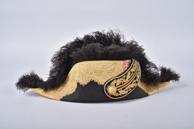 black and gold feathered hat with a mustache on top of it