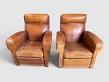 deux fauteuils inclinables en cuir marron placés côte à côte sur une surface grise