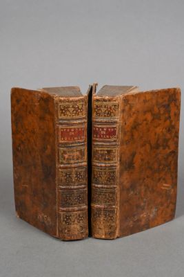 two old books sitting on top of each other on a table