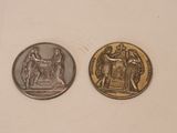 two silver and gold coins sitting on top of a white surface