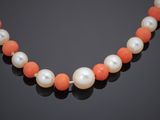 an orange and white pearl necklace on a black surface