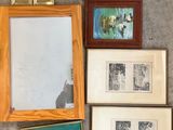 many framed pictures on the floor next to a clock