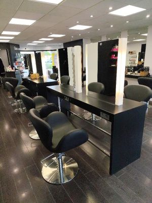 a photo of a salon with black chairs and tables