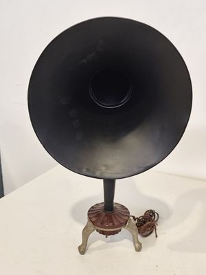 une enceinte noire posée sur une table, à côté d'une paire de chaussures