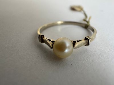 an image of a ring with a pearl in it on a table