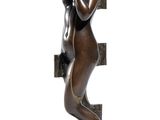 bronze statue of a woman holding a book and leaning against a wall