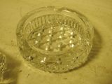 a glass ashtray sitting on a table next to an ice cube